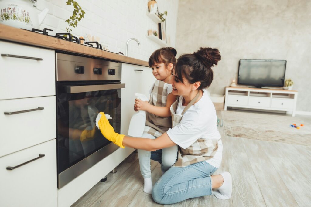 A little girl and her mother are cleaning the kitchen